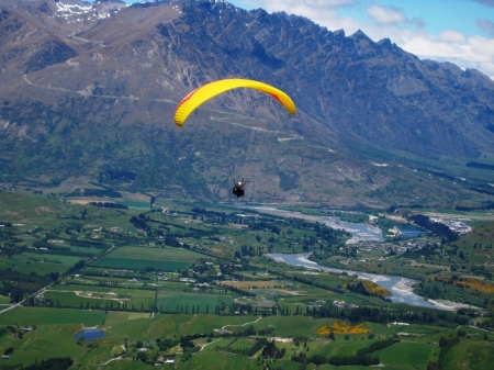 Paragliding over the Arrow River valley with the Remarkables mountain range in the distance.